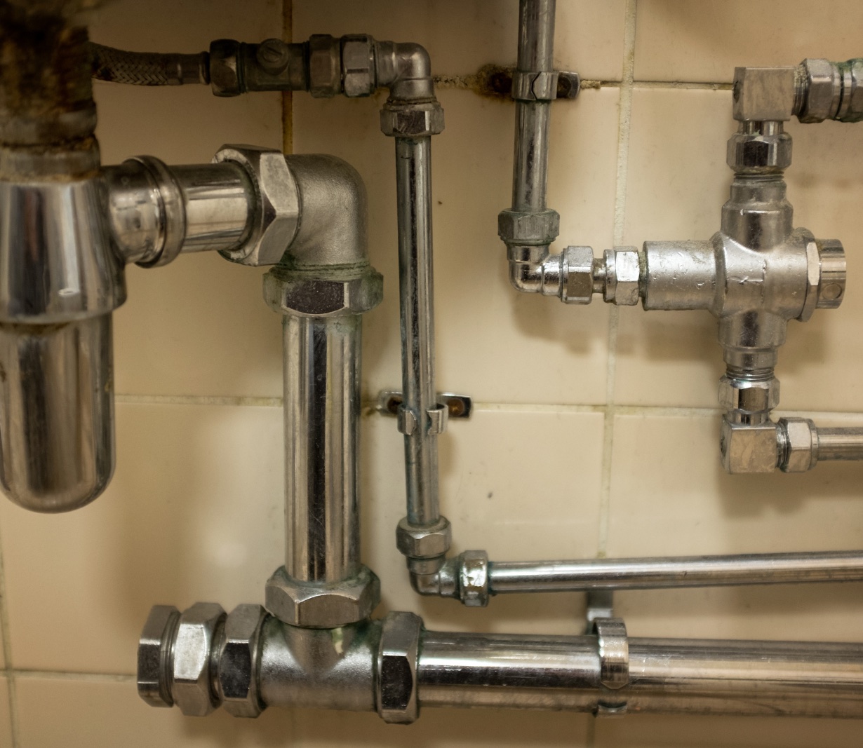 A detailed view of plumbing pipes and connections beneath a sink